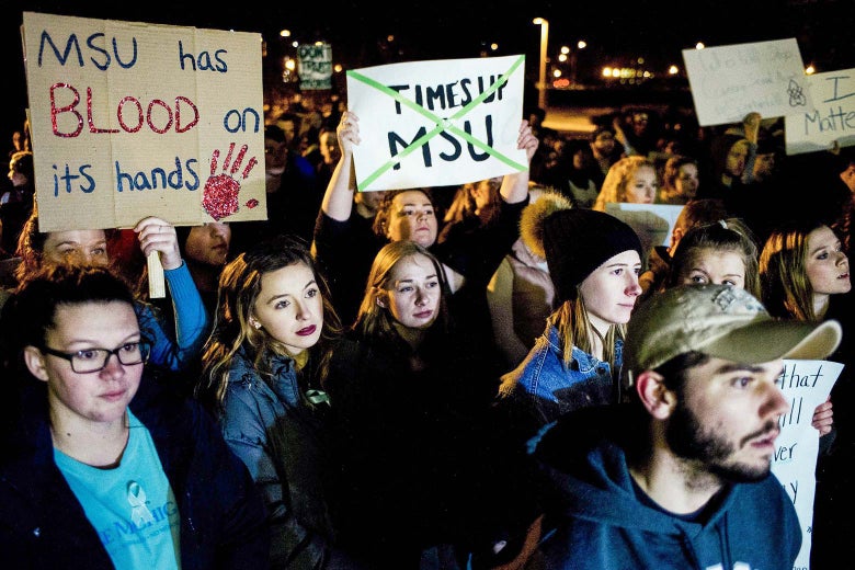 Livonia sophomore Jessica Smith, second from left, and Lindsey Cross rally alongside Michigan State University students that march to the steps of the administration building as they rally in support of sexual assault survivors on campus, on Friday, Jan. 26, 2018, in East Lansing, Mich.